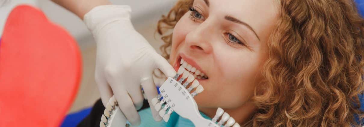 dentist-comparing-patient-s-teeth-shade-with-samples-bleaching-treatment