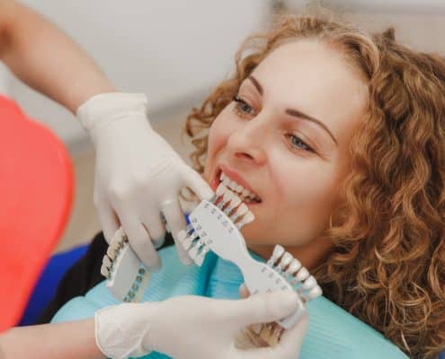 dentist-comparing-patient-s-teeth-shade-with-samples-bleaching-treatment